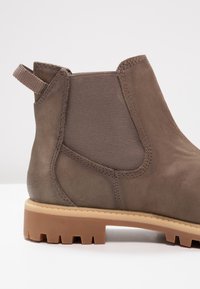 Braune Leder-Stiefelette mit elastischen seitlichen Einsätzen, strukturiertem Obermaterial und einer robusten Gummisohle mit Traktionsprofil.