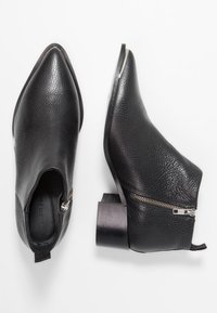 Schwarze Lederstiefeletten mit strukturiertem Oberflächen, spitzer Zehenform und einem robusten Absatz. Verfügt über einen seitlichen Reißverschluss und einen stabilen Zugtab, um das Anziehen zu erleichtern.