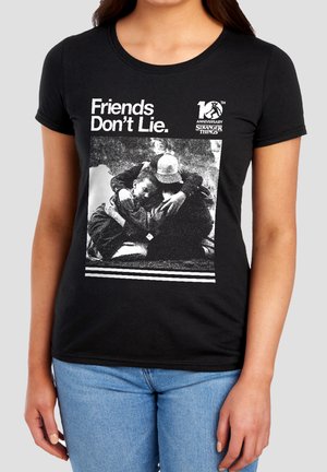 Black T-shirt with text "Friends Don't Lie" and a black and white photo of two people hugging, celebrating Stranger Things 10th anniversary.