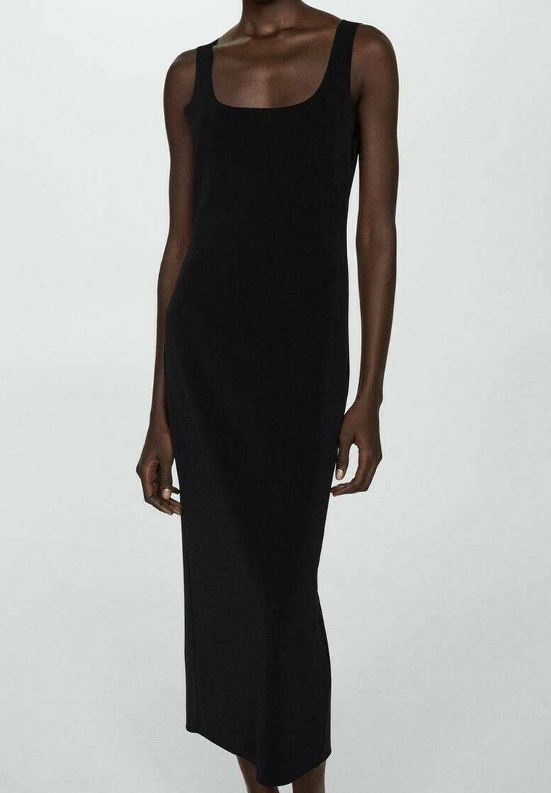 Femme portant une robe midi noire ajustée sans manches avec un col carré, debout devant un fond uni gris clair.