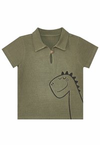 Olivgrön kortärmad polo med krage, prydd med ett svart dinosauriemönster och en träknapp vid halslinningen.