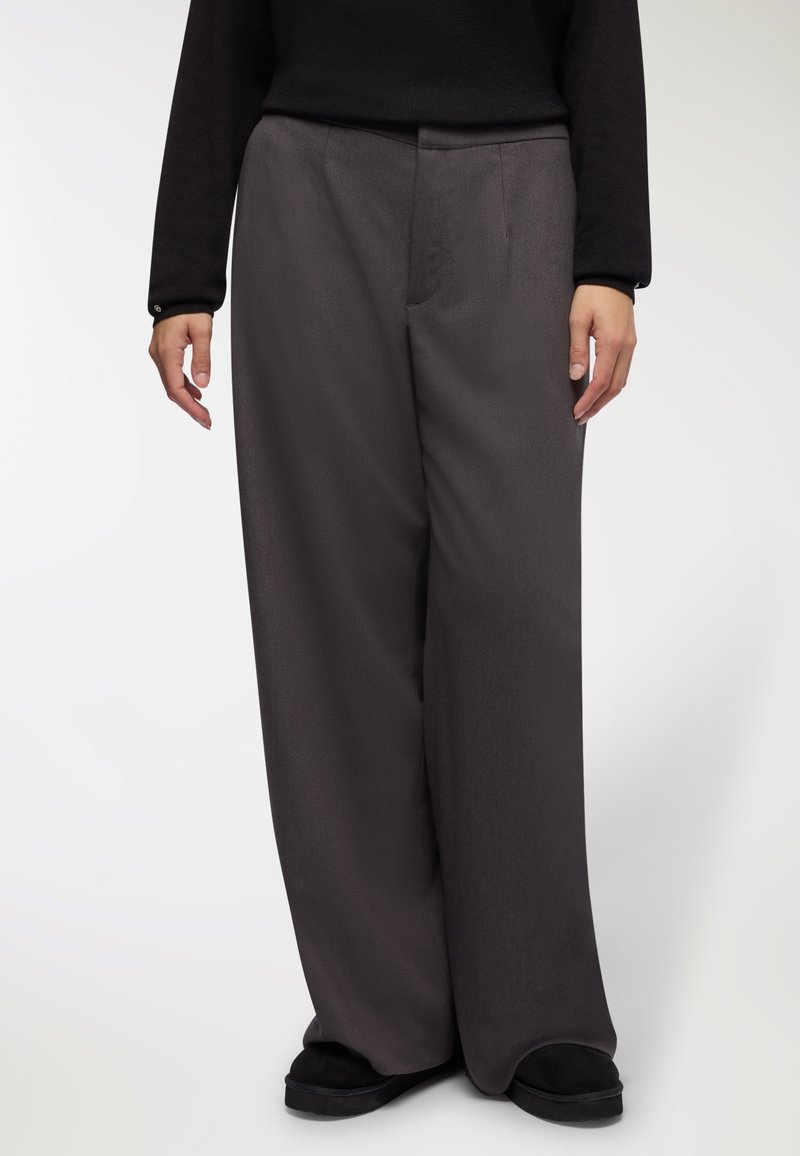Pantaloni a gamba larga in tessuto grigio scuro, con una texture liscia, frontale piatto e tasche laterali. La vita è plissettata per una vestibilità su misura.