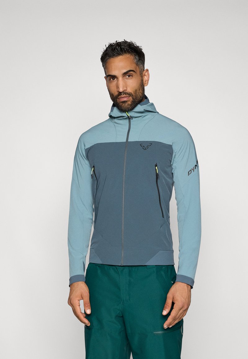 Könnyű technikai dzseki kéttónusú kék színben. Jellemzői a cipzáras elülső rész, kapucni, cipzáras zsebek és a textúrált felület a ujjakon.