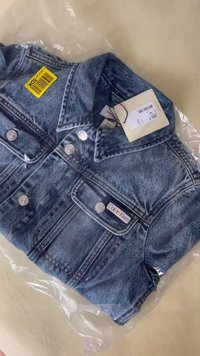 Svijetloplava traper jakna sa srebrnim gumbima, dva džepa na prsima i oznakom Calvin Klein. Zapakirana u prozirnu plastiku.