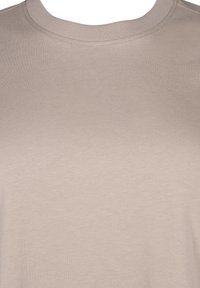 Camiseta de cuello redondo beige hecha de un tejido de algodón suave. Presenta un diseño simple con mangas cortas y detalles de costura mínimos.