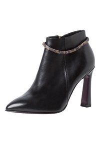 Svart läderankelboot med spetsig tå, hög klack och en dekorativ metallkedja runt kragen. Slät yta med subtil glans.