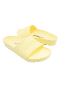 Chanclas de goma amarillas con una tira texturizada y un logo estampado. Las suelas tienen un diseño de dibujo para mayor adherencia.