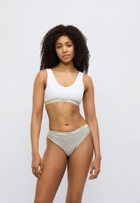 Λευκό βαμβακερό αθλητικό σουτιέν με μπεζ ζώνη Calvin Klein, συνδυασμένο με ανοιχτό γκρι βαμβακερό τρίγωνο, και τα δύο με λεία υφή.