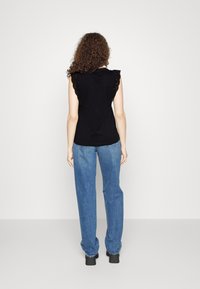 Sort ærmeløs top med blonder ved skuldrene, parret med højtaljede blå jeans. Outfittet har en afslappet pasform og ensfarvede nuancer.
