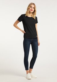 Sort kortærmet t-shirt med rund hals, parret med mørk denim skinny jeans. Strukturerede hvide sneakers fuldender outfittet.