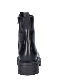 Zwarte leren enkelboot met een stevige zool, achterste ritssluiting en een gladde textuur. Voorzien van een ronde neus en minimale stikseldetails.