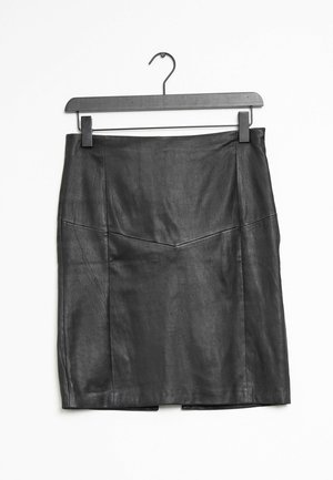 Jupe noire en similicuir longueur genou avec détails de coutures, suspendue sur un cintre noir à clips sur fond blanc.