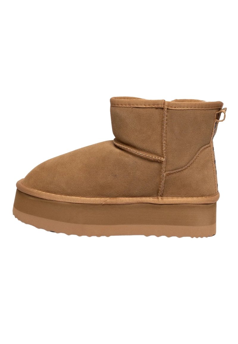 Stivale da caviglia in suede marrone con punta tondeggiante, design minimalista, gambale corto e suola in gomma spessa e texture. Include un piccolo inserto per il tallone.