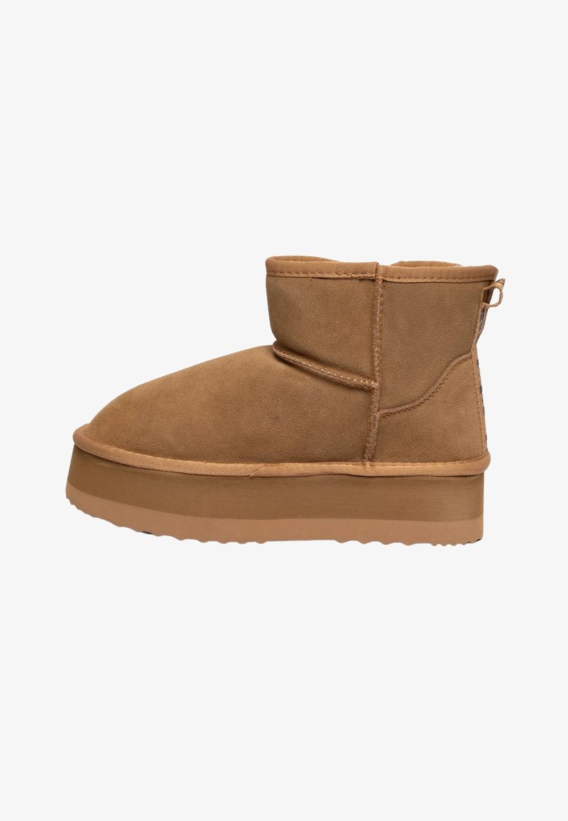 Stivale da caviglia in suede marrone con punta tondeggiante, design minimalista, gambale corto e suola in gomma spessa e texture. Include un piccolo inserto per il tallone.