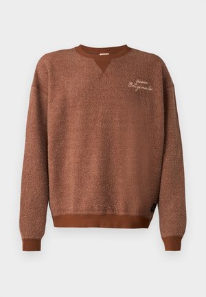 Sweatshirt castanho com um acabamento texturizado, apresentando um design em V e punhos canelados. Etiqueta bordada com a inscrição "Guess Originals".