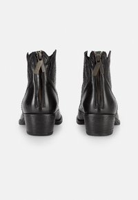 Botas de tobillo de cuero negro con un acabado texturizado, que cuentan con una cremallera lateral, un borde superior curvado y un tacón bajo apilado.