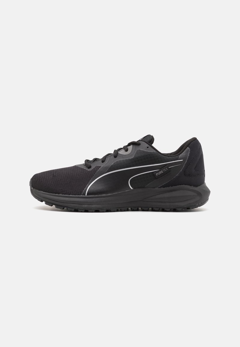Zapatilla deportiva negra con parte superior de malla, diseño texturizado, acentos reflectantes y una suela de goma gruesa. Presenta cordones y un cuello acolchado.
