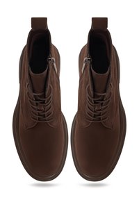 Botas de ante marrón hasta el tobillo con punteras redondeadas, cordones, cremalleras laterales y lengüetas, mostradas desde una vista superior sobre un fondo blanco.