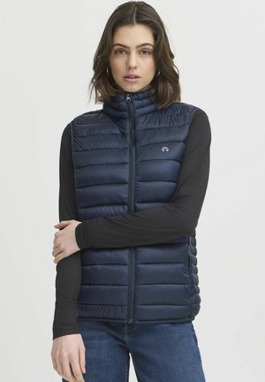 Gilet imbottito blu navy con colletto alto, trapuntatura orizzontale e zip frontale. Presenta un piccolo logo sul lato sinistro del petto, abbinato a maniche lunghe.