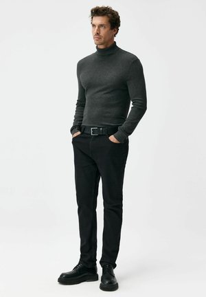 Ciemnoszary sweter z golfem, dopasowany krój, zestawiony z czarnymi jeansami i czarnymi sznurowanymi butami. Gładka faktura, proste akcenty, bez wzorów.