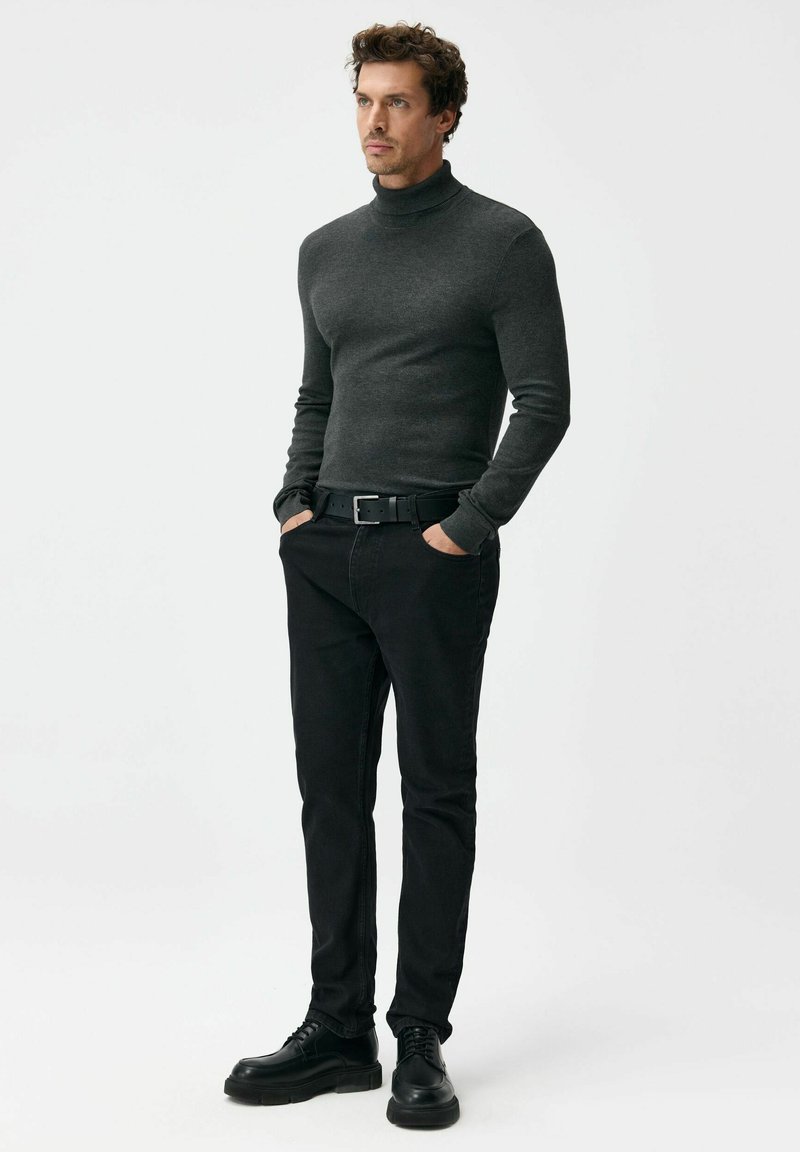 Ciemnoszary sweter z golfem, dopasowany krój, zestawiony z czarnymi jeansami i czarnymi sznurowanymi butami. Gładka faktura, proste akcenty, bez wzorów.