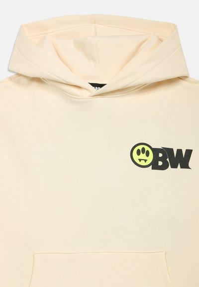 Lys beige hettegenser med frontlomme og svart "OBW"-tekst ved siden av en gul sirkel med et poteavtrykk og vampyrtenner på brystet.