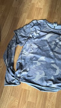 Hosszú ujjú szürke terepmintás póló, puha anyagból készült, lekerekített nyakkivágással, és látható varrásokkal az ujjaknál és alján.