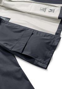 Interno della giacca impermeabile blu navy, caratterizzato da una fodera chiara, una tasca con zip e icone di manutenzione. Texture liscia e elementi di design funzionali.