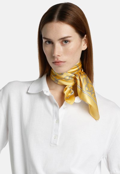 Geel zijden sjaal met een touwpatroon, keurig om de hals geknoopt, gecombineerd met een witte blouse met kraag, soepele textuur en levendige kleur.