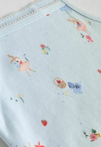 Helles blaues Gewebe mit einer weichen Textur, versehen mit einem verspielten Muster aus Hasen, Blumen, Erdbeeren und Schmetterlingen. Mit zartem Besatz dekoriert.