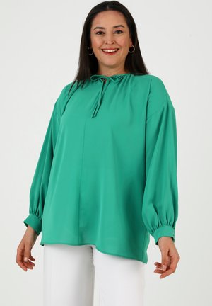 Green blouse with a round neckline, tie detail, and long balloon sleeves. Made of smooth fabric, features a relaxed fit and curved hem.