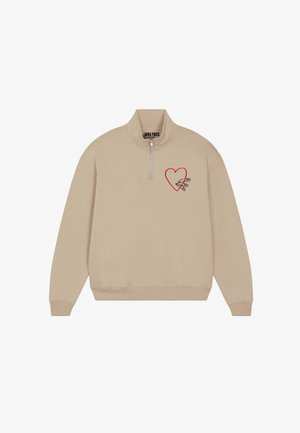 Felpa beige con collo a mezza zip. Presenta una grafica di un cuore rosso e schizzi di spille di sicurezza sul petto sinistro. Tessuto dalla consistenza morbida.