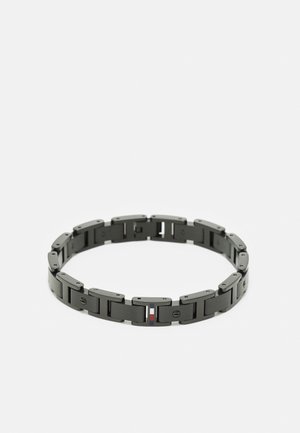 Bracelet à maillons en métal noir avec des segments rectangulaires et de petites vis décoratives, comportant un petit détail rayé coloré sur un maillon.