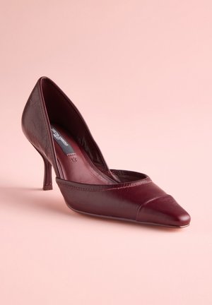 Bordeauxrød læderpumpe med spids tå og buet remdetalje, med en slank hæl og en subtil tekstureret finish.