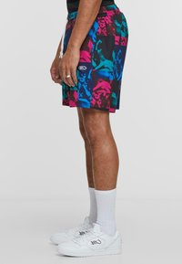 Swim shorts in a colorful graphic pattern with shades of pink, blue, and black. Features an elastic waistband with a drawstring.