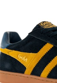 Navyblaue Wildleder Sneaker mit gelben Streifen, strukturiertem Obermaterial, Gola-Branding an der Seite und einer beige Gummisohle.