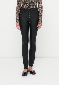 Zwarte high-waisted skinny jeans met een knoopsluiting en vier voorzakken. Het materiaal lijkt rekbaar met een gladde textuur.