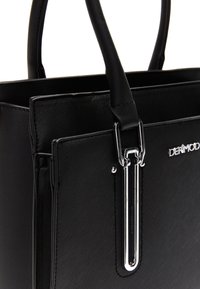 Sac à main noir en simili cuir texturé avec deux poignées. Présente un détail de fermoir en argent et le nom de la marque "DeriMod" en relief.