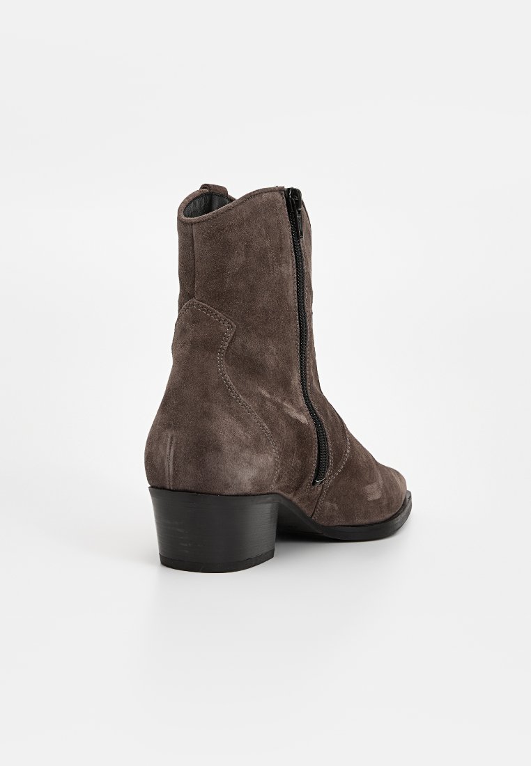 Stivali alla caviglia in suede marrone scuro, con zip laterale, punta arrotondata e tacco basso a blocco. Texture liscia con un leggero lucido.