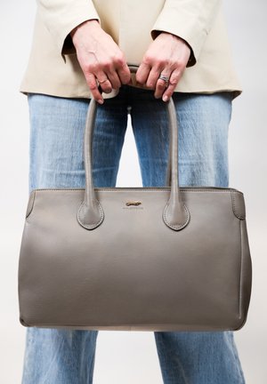 Sac fourre-tout en cuir gris avec des poignées arrondies et des détails de couture subtils. Texture lisse et design minimaliste, adapté à un usage polyvalent.