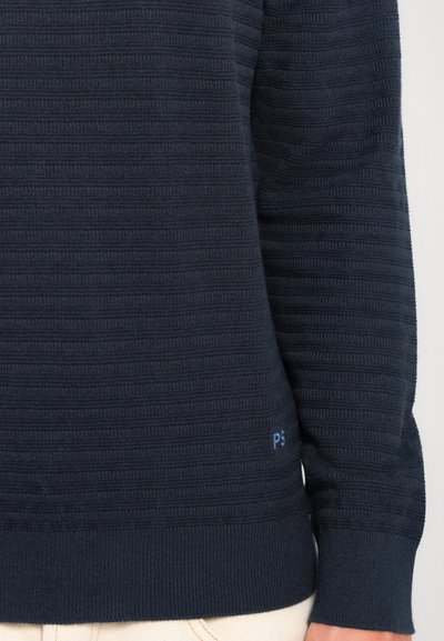 Navy blå teksturert genser med horisontalt ribbemønster, med en liten "PS"-logo nær bunnen på venstre side.