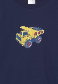 Marineblaues Baumwoll-T-Shirt mit einem bunten Motiv eines gelben Dump-Trucks, der graue Steine in seiner Ladefläche hat und rote Akzente an den Rädern.