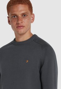Dunkelgrauer gestrickter Pullover mit Rundhalsausschnitt. Verfügt über ein kleines oranges Logo auf der Brust und einen strukturierten Stoff mit gerippten Bündchen und Saum.