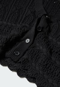 Zwarte gebreide cardigan met ingewikkelde textuurpatronen, voorzien van een rij van drie zwarte knopen en een geschulpte zoom.