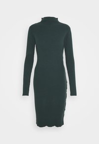 Musta vihreä ribbiknitti mekko, jossa on korkea kaulus, pitkät hihat, slim fit ja aaltoileva helma, sekä sivuhalkio nappikoristeilla.