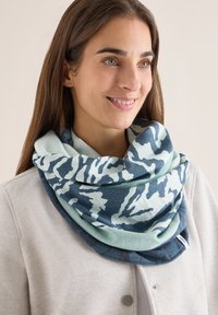 Multifarvet infinity-scarf i blødt stof med et blåt og mintfarvet camouflage-mønster; glat tekstur med en let glans.