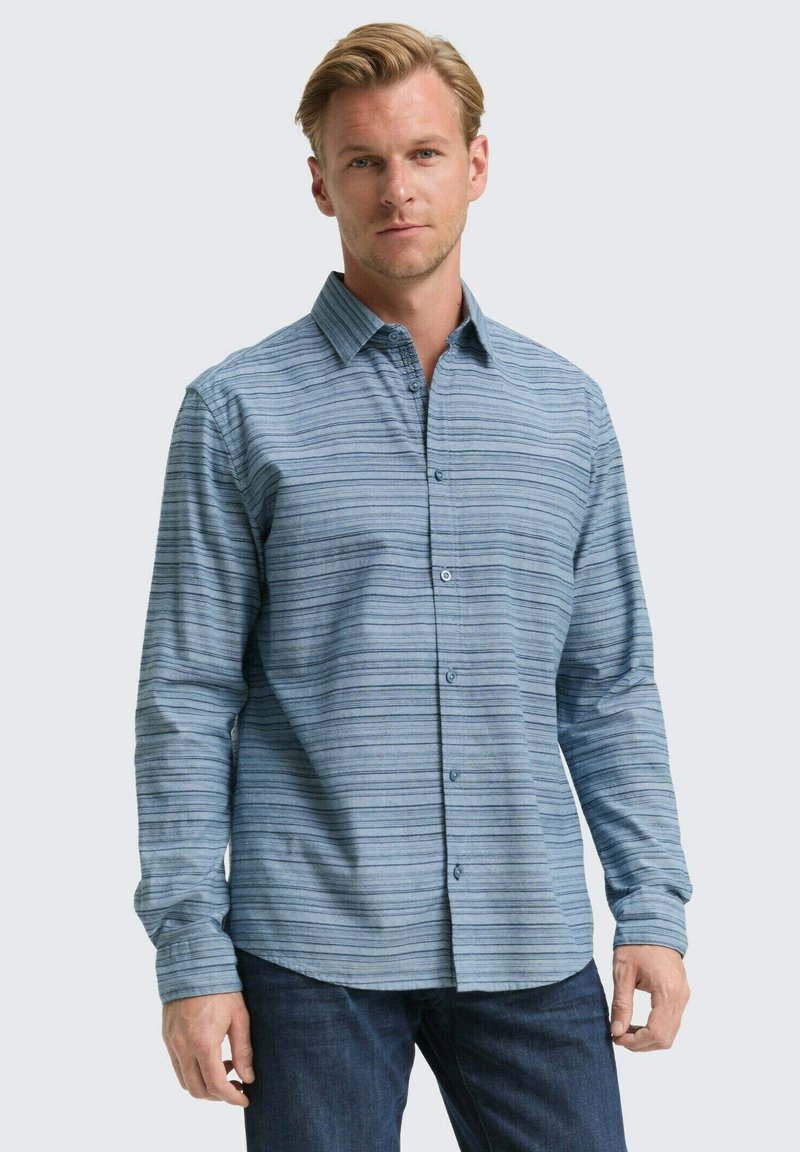 Lichtblauw overhemd met lange mouwen, verticale strepen, knoopsluiting, kraag en gestructureerde stof. Gecombineerd met donkerblauwe jeans.