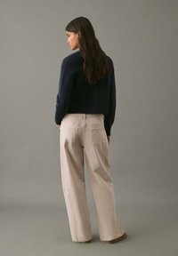Suéter corto azul marino combinado con pantalones de pierna ancha beige. El suéter tiene un acabado texturizado, mientras que los pantalones cuentan con bolsillos traseros y un corte relajado.