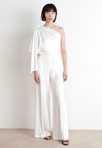 White satin one-shoulder jumpsuit with a draped sleeve and wide-leg design. Smooth texture with a seamless finish and subtle sheen.