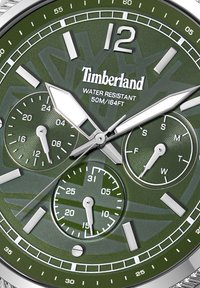 Chronografové hodinky so zeleným ciferníkom a striebornými akcentmi, ktoré majú tri subciferníky a výraznú značku 12. Vodotesné do hĺbky 50 m.